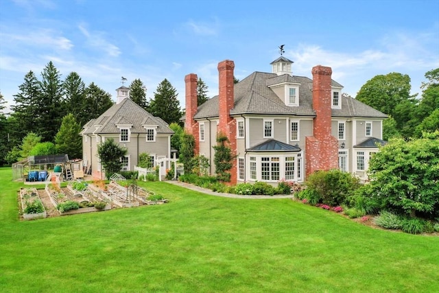 back of property featuring a vegetable garden, a lawn, and an outdoor structure