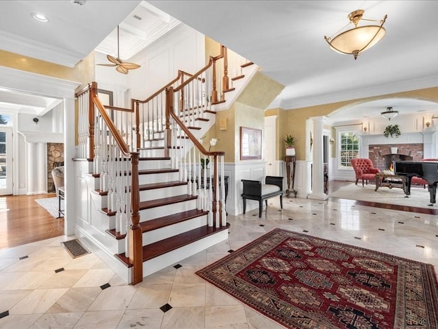 stairs with a decorative wall, visible vents, wainscoting, decorative columns, and crown molding