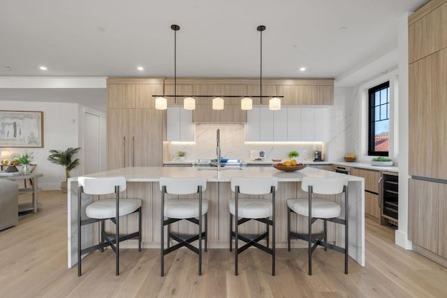 kitchen featuring a kitchen breakfast bar, an island with sink, and hanging light fixtures