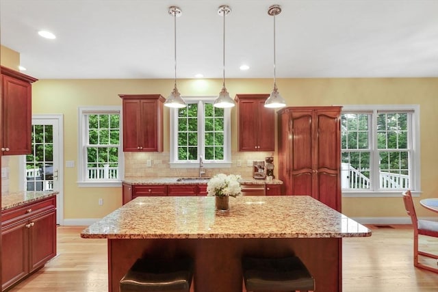 15 Sylvan Dr, Stow, MA 01775 - kitchen with baseboards, light wood finished floors, a breakfast bar, backsplash, and recessed lighting