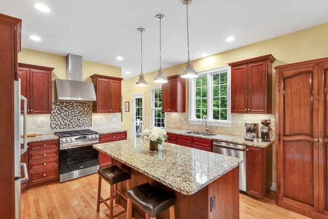 15 Sylvan Dr, Stow, MA 01775 - kitchen with stainless steel appliances, wall chimney range hood, a sink, light wood-type flooring, and a kitchen island