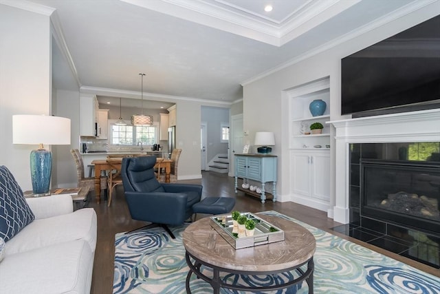 living area featuring dark wood-type flooring, crown molding, a tile fireplace, baseboards, and recessed lighting