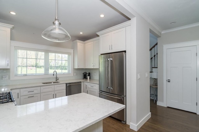 kitchen with appliances with stainless steel finishes, a sink, tasteful backsplash, dark wood finished floors, and white cabinetry