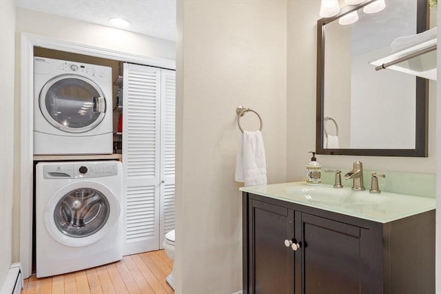 163 Candlestick Rd, North Andover, MA 01845 - laundry area with stacked washer / dryer, a baseboard heating unit, and light wood finished floors