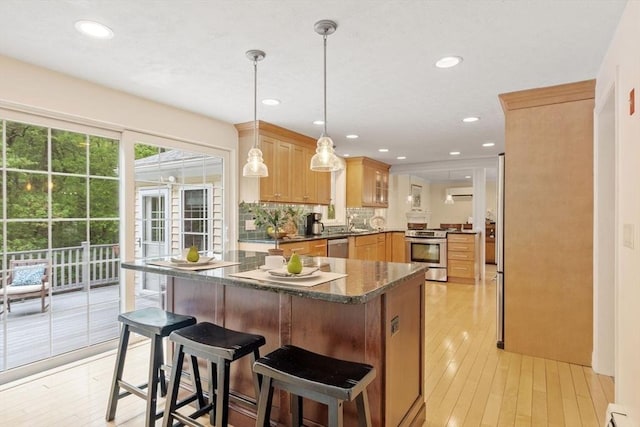 163 Candlestick Rd, North Andover, MA 01845 - kitchen with appliances with stainless steel finishes, dark countertops, light wood finished floors, a breakfast bar area, and backsplash