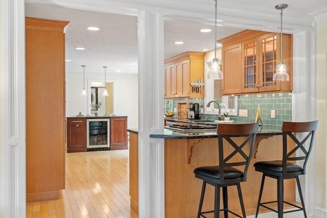 163 Candlestick Rd, North Andover, MA 01845 - kitchen with wine cooler, a peninsula, glass insert cabinets, decorative backsplash, and light wood-style flooring
