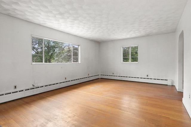 14 Forty Steps Ln, Nahant, MA 01908 - empty room with light wood-style floors, a textured ceiling, arched walkways, and a baseboard radiator