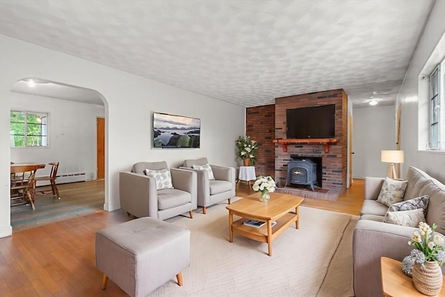 14 Forty Steps Ln, Nahant, MA 01908 - living area featuring arched walkways, light wood-style flooring, a wood stove, baseboard heating, and a textured ceiling