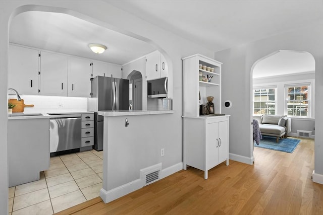 230 Beal Rd, Waltham, MA 02453 - kitchen featuring arched walkways, appliances with stainless steel finishes, light countertops, and white cabinets