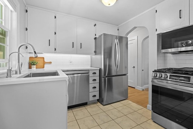 230 Beal Rd, Waltham, MA 02453 - kitchen with stainless steel appliances, a sink, arched walkways, light tile patterned floors, and backsplash