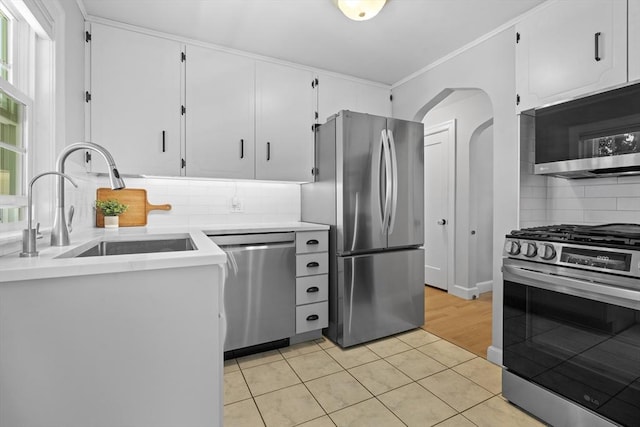 230 Beal Rd, Waltham, MA 02453 - kitchen with appliances with stainless steel finishes, a sink, arched walkways, light tile patterned flooring, and backsplash