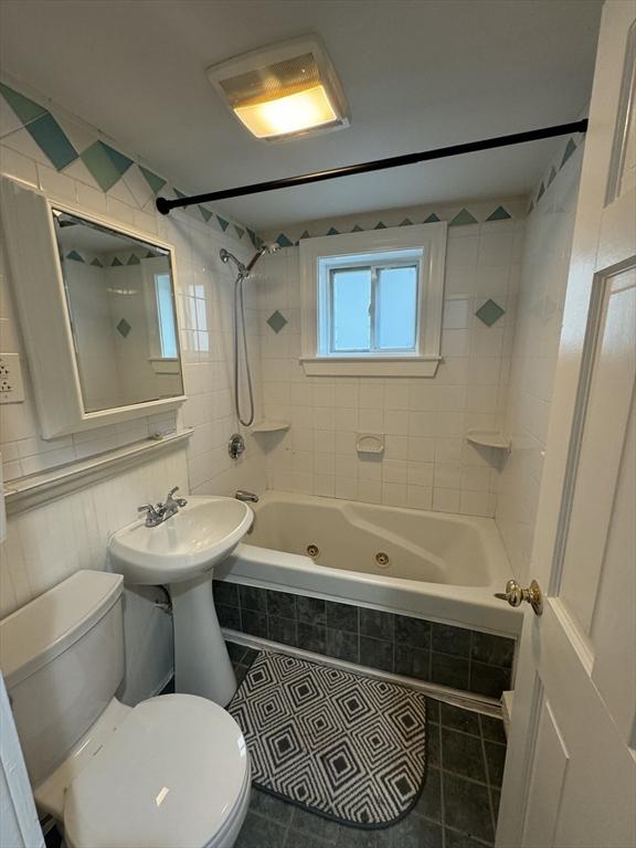 bathroom with tile patterned floors, tiled shower / bath combo, and toilet