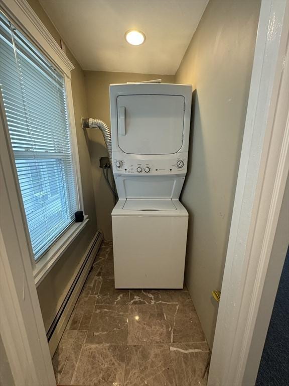 laundry room featuring stacked washer and dryer and a baseboard heating unit