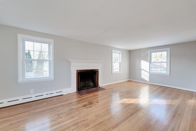 unfurnished living room with a fireplace, light hardwood / wood-style flooring, and a baseboard heating unit