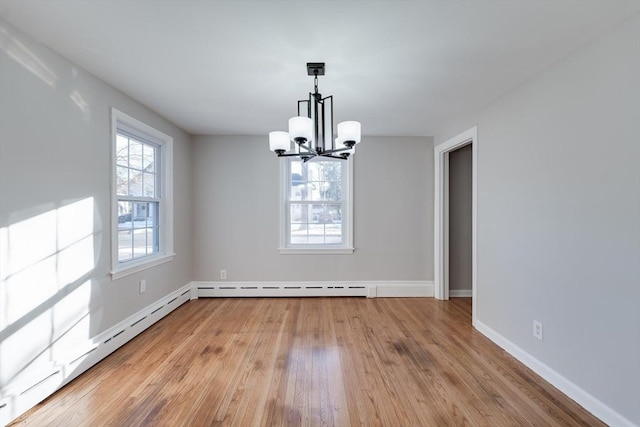 unfurnished dining area with a notable chandelier, a baseboard heating unit, and light wood-type flooring