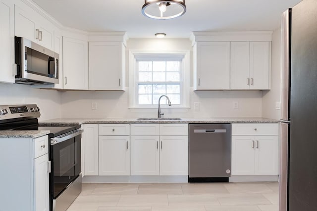 kitchen with stainless steel appliances, white cabinetry, sink, and light stone counters