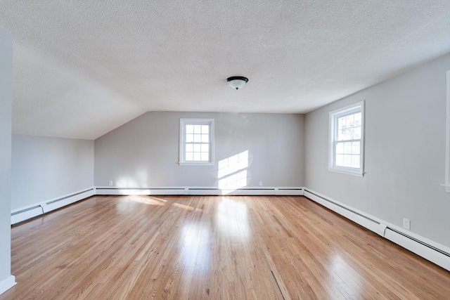 bonus room with a textured ceiling, vaulted ceiling, baseboard heating, and light wood-type flooring