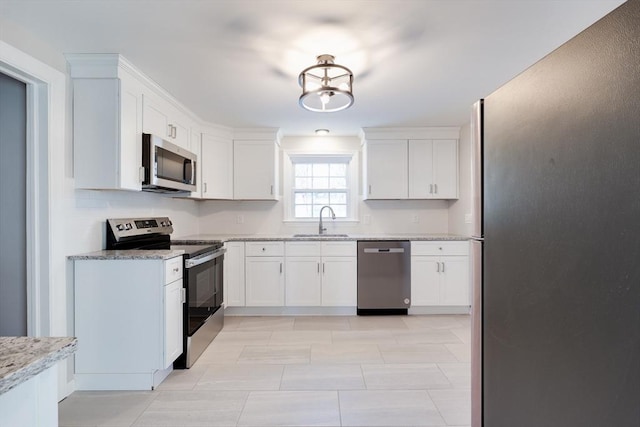 kitchen featuring white cabinetry, appliances with stainless steel finishes, sink, and light stone counters