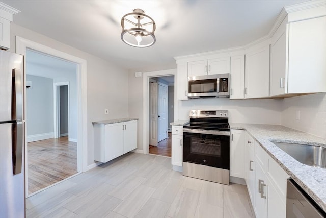 kitchen with light stone counters, stainless steel appliances, and white cabinets