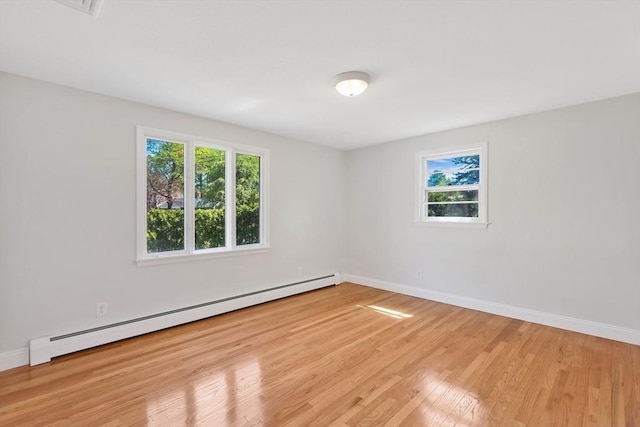 unfurnished room with baseboards, plenty of natural light, baseboard heating, and light wood-style flooring