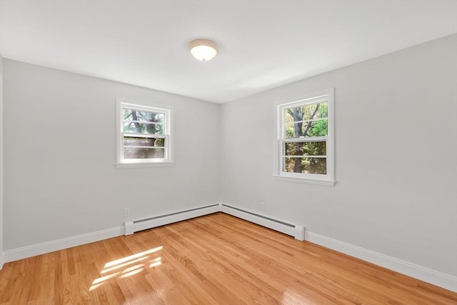 unfurnished room featuring baseboards, light wood-style flooring, and a baseboard radiator