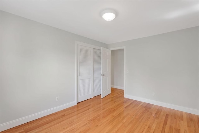 unfurnished bedroom with baseboards, light wood finished floors, and a closet
