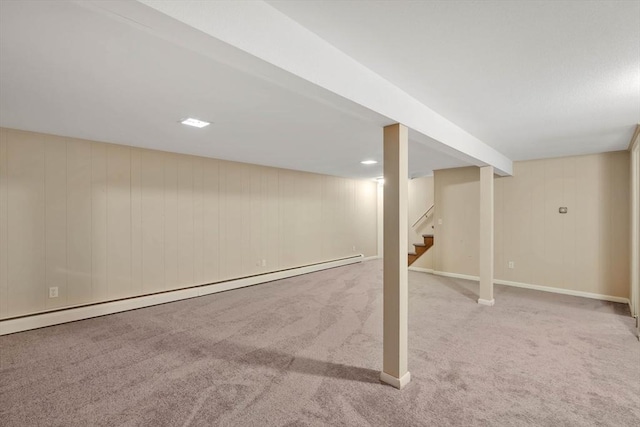 finished basement featuring baseboards, carpet flooring, stairs, and a baseboard heating unit