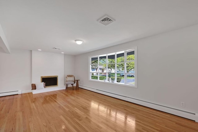 unfurnished living room featuring baseboards, a baseboard radiator, light wood-type flooring, and visible vents