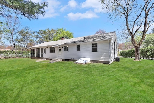 back of house with a sunroom, a yard, a chimney, and entry steps