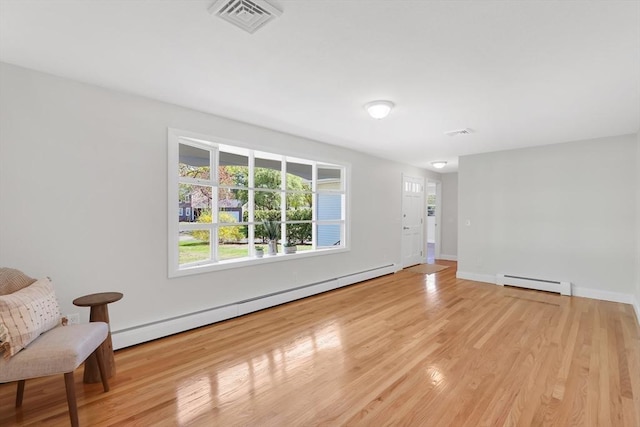 living room featuring visible vents, light wood finished floors, a baseboard heating unit, and baseboard heating