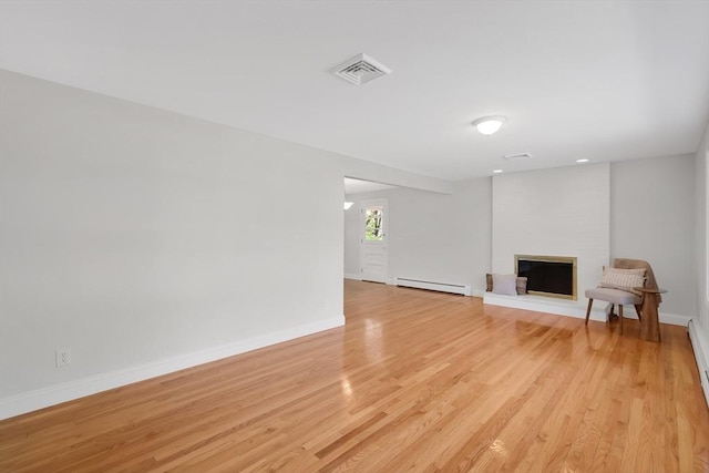 unfurnished living room with baseboards, a baseboard radiator, light wood-style flooring, and visible vents