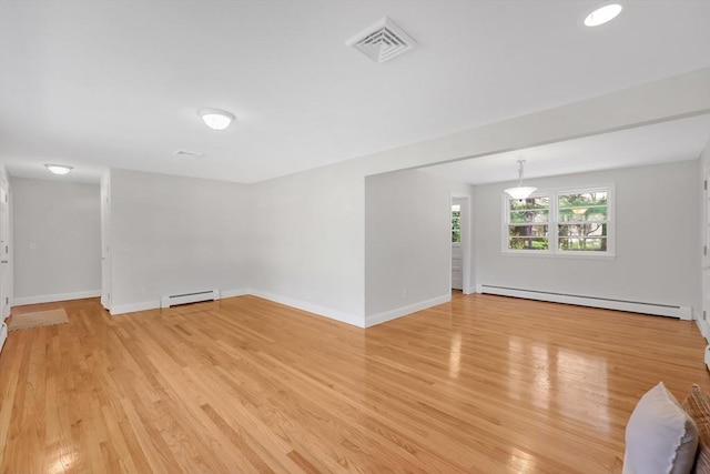 empty room with baseboards, a baseboard heating unit, light wood-style flooring, and visible vents