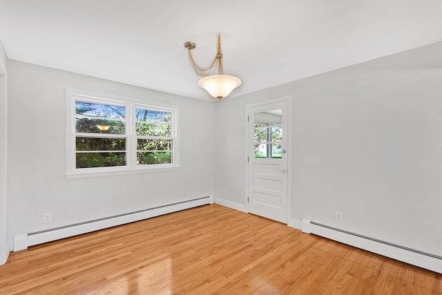 unfurnished room featuring baseboards, a baseboard heating unit, and light wood-style floors