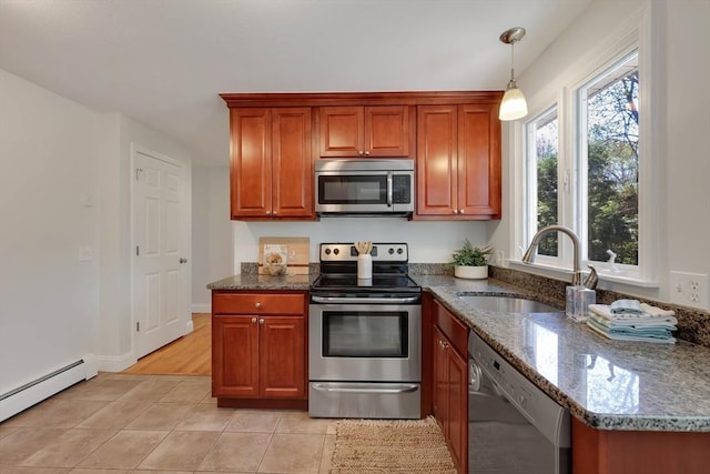 kitchen with a sink, a baseboard radiator, dark stone counters, stainless steel appliances, and light tile patterned flooring