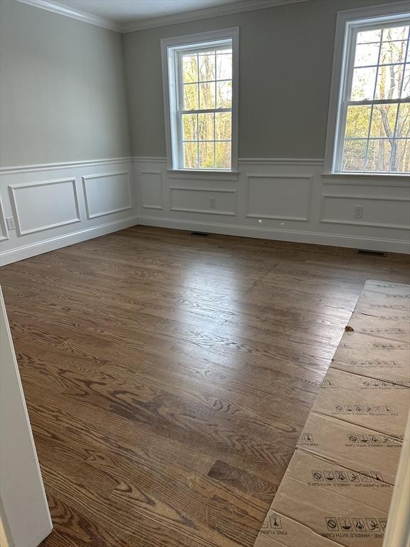 empty room featuring dark wood-type flooring, crown molding, and a wealth of natural light