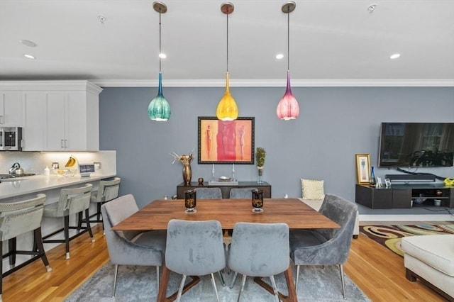 dining area with ornamental molding, light wood finished floors, and recessed lighting