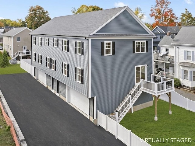 view of front of property featuring driveway, a shingled roof, stairs, fence, and a front lawn