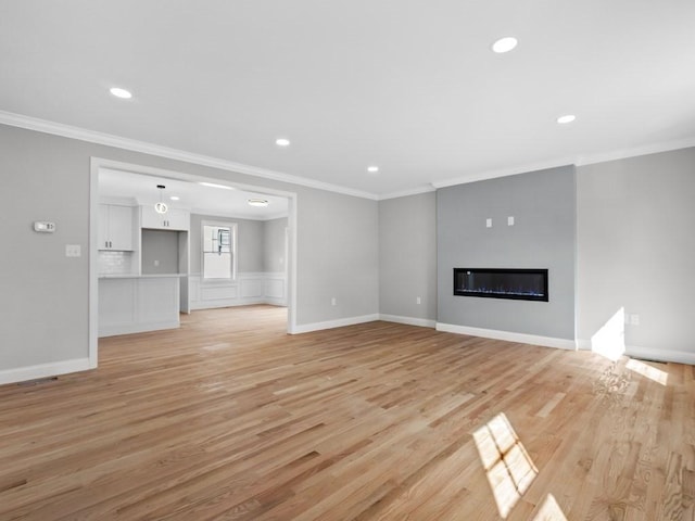 unfurnished living room featuring recessed lighting, a glass covered fireplace, light wood-style flooring, and crown molding