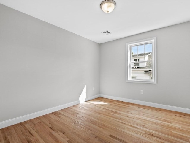 unfurnished room featuring baseboards, visible vents, and wood finished floors