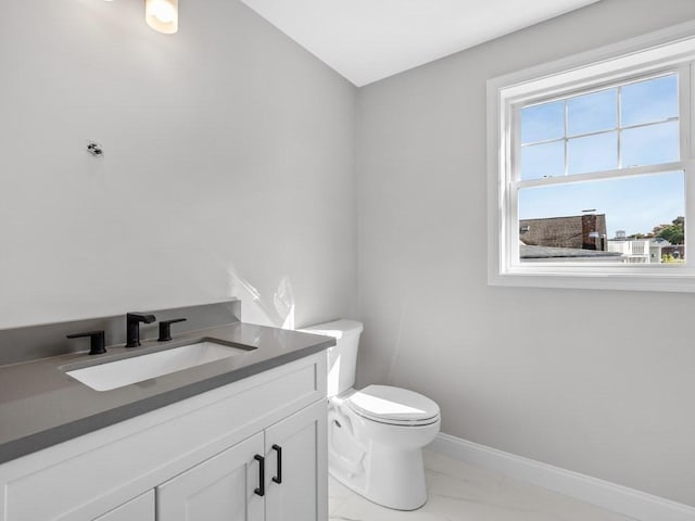 bathroom featuring marble finish floor, vanity, toilet, and baseboards