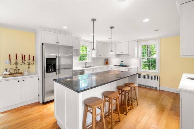 32 School St, Belmont, MA 02478 - kitchen with stainless steel appliances, radiator, a sink, white cabinetry, and crown molding