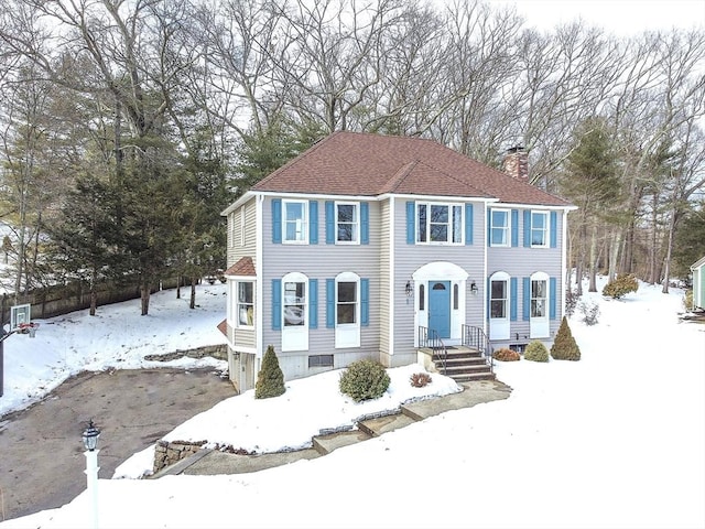 view of front of home with a chimney and roof with shingles