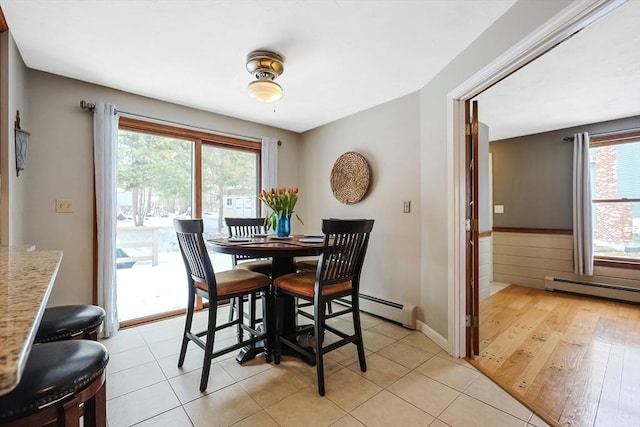 dining space featuring light tile patterned floors, a baseboard radiator, and wainscoting