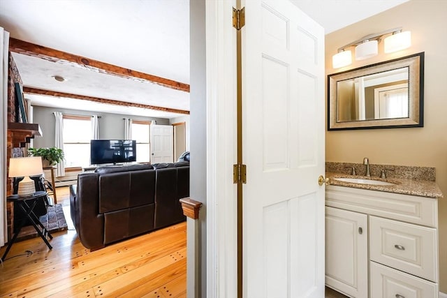 interior space with light wood finished floors, indoor wet bar, and beam ceiling