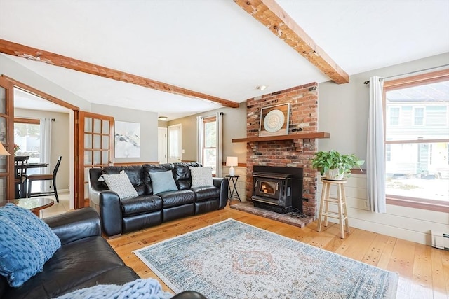 living area with a wood stove, beamed ceiling, and light wood-style flooring