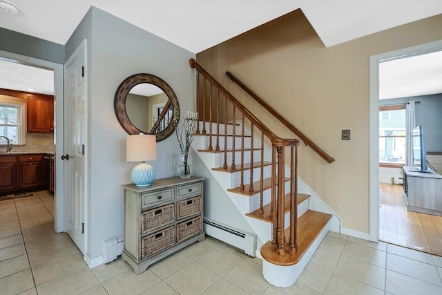 stairway with a baseboard heating unit, a baseboard radiator, tile patterned flooring, and a healthy amount of sunlight