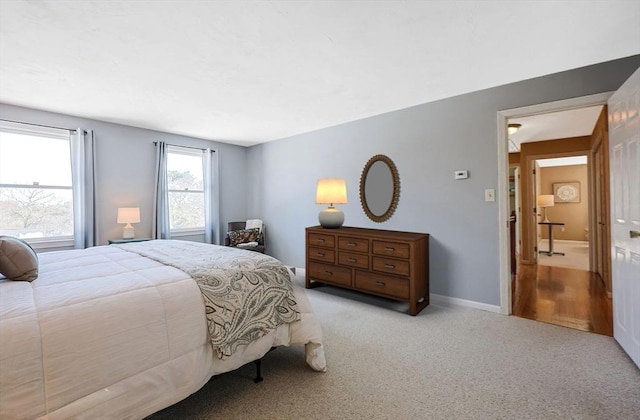 bedroom with baseboards and light colored carpet