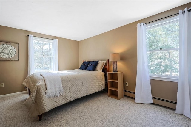 bedroom with a baseboard heating unit, multiple windows, light carpet, and baseboards