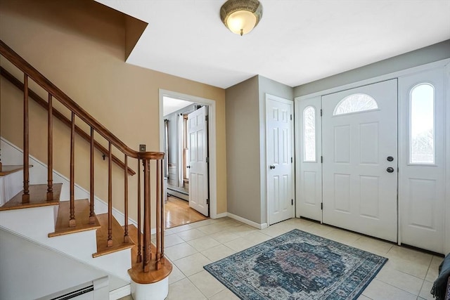 foyer with light tile patterned floors, stairway, baseboard heating, and baseboards