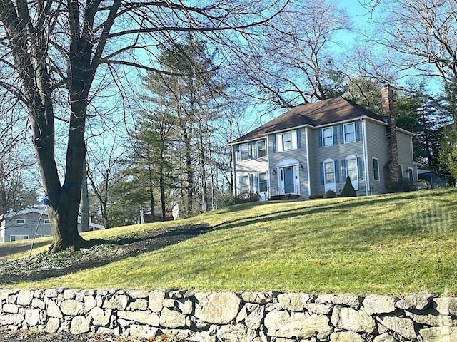 colonial home with a chimney and a front yard